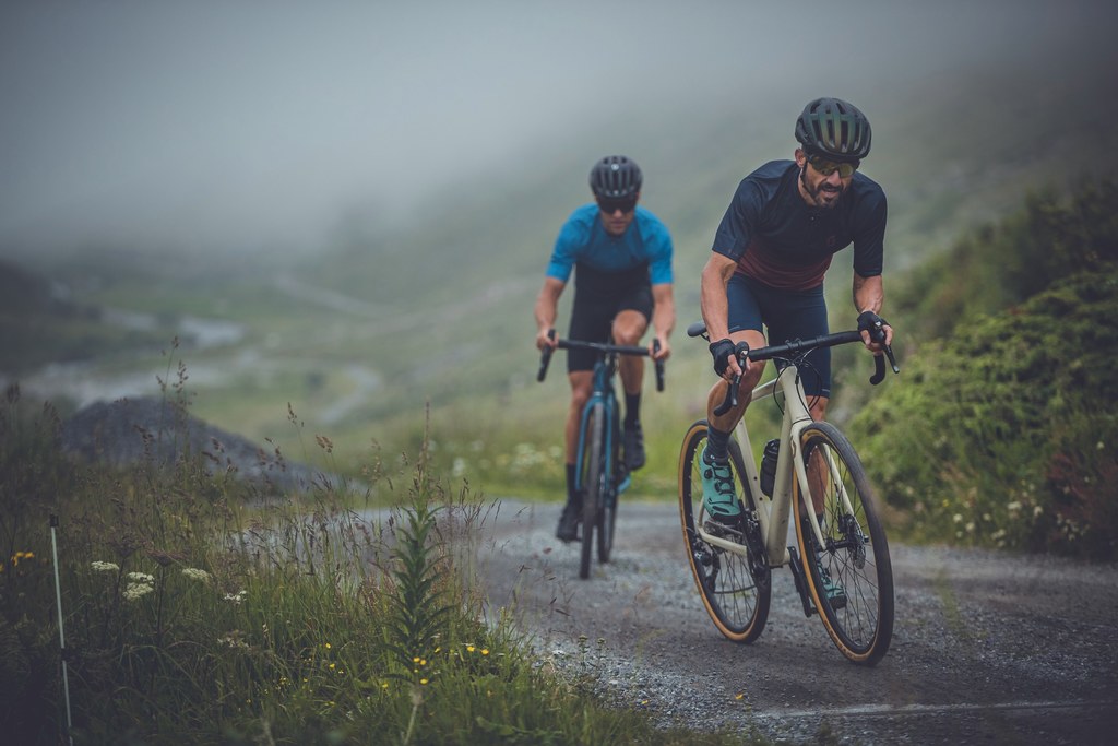 Zwei Radfahrer, die bei düsterem Wetter einen Berg hoch fahren mit Gravelbikes