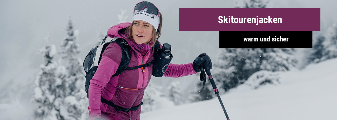 Junge Frau die mit Tourenski auf einen Berg steigt im Tiefschnee