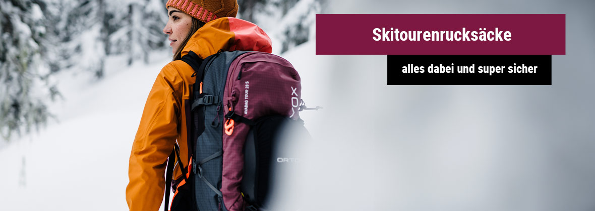 Person in orangefarbener Jacke mit Skitourenrucksack im verschneiten Wald, daneben ein Banner mit der Aufschrift 'Skitourenrucksäcke - alles dabei und super sicher'.