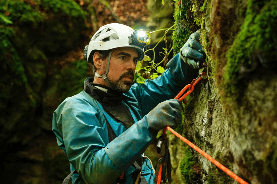 Kletterer mit Helm, Seil und Karabiner an einer Felswand