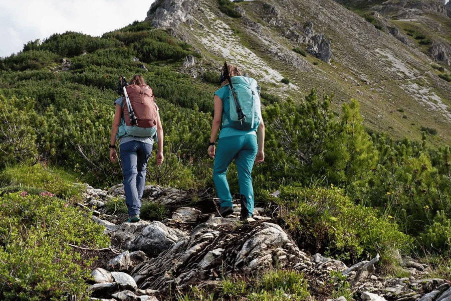Zwei Wanderinnen mit Wanderrucksäcken auf einem alpinen Bergweg
