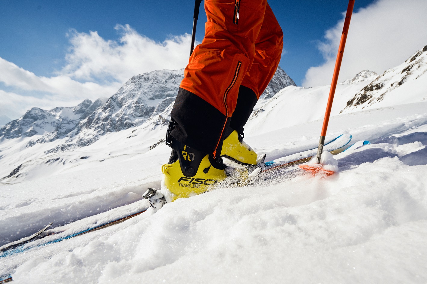 Nahaufnahme eines Skitourenstiefels in Aktion auf einer verschneiten Piste.